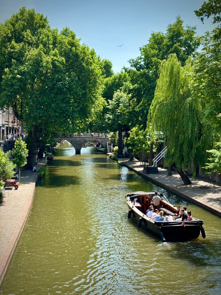 Houten sloep met schipper vaart door de Oudegracht in Utrecht langs de werfkelders bij schemering